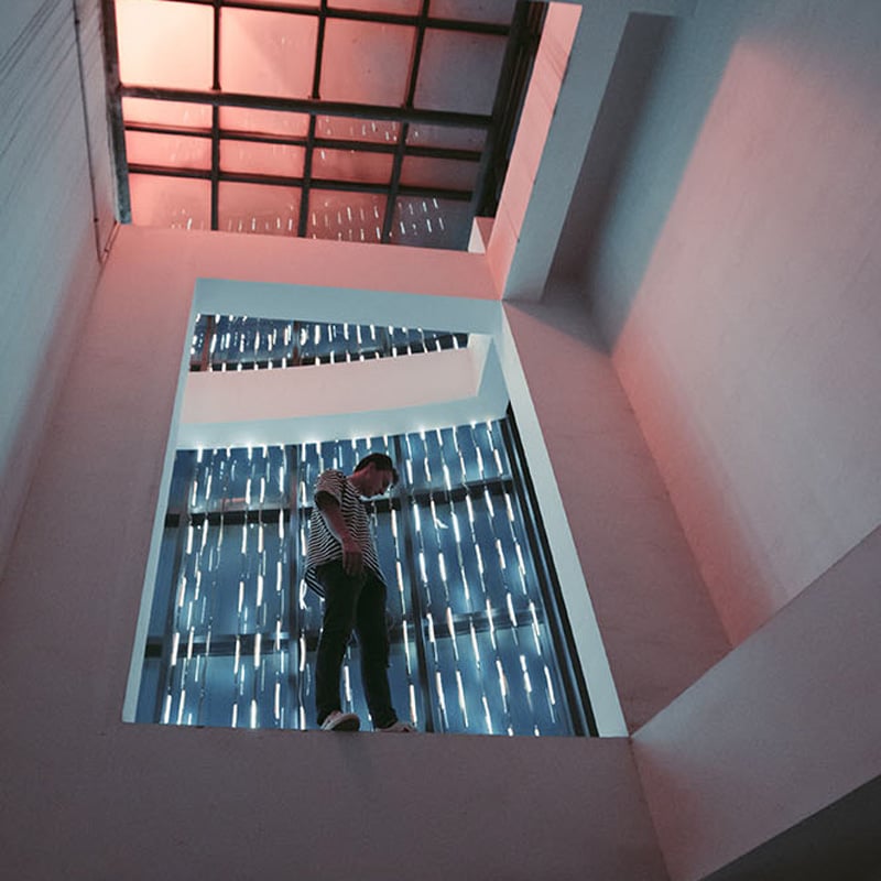 Angled shot of a person standing in front of a large window.